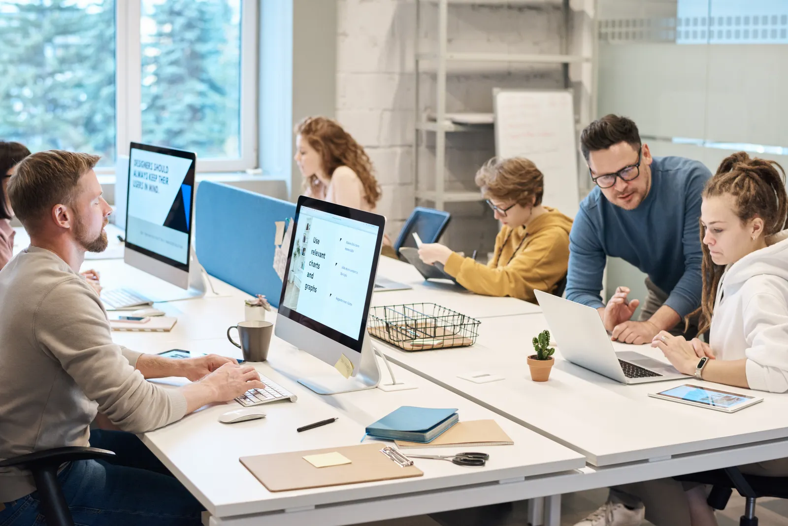 Colleagues collaborating at computers in a modern office.