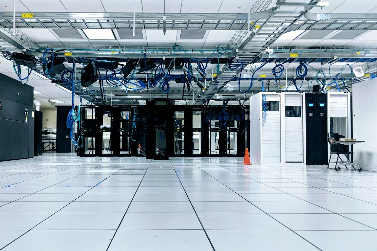 Rows of server cabinets connected by overhead network cabling